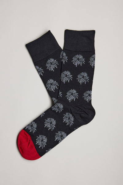A pair of Barkers Hudson Firework Socks—black cotton socks with a white firework burst pattern and bright red toes—are laid flat on a neutral background.