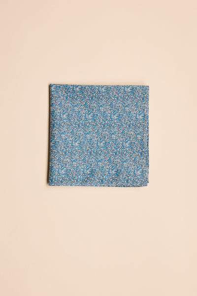 The Barkers Floral Pocket Square, neatly folded, displays its subtle navy floral cotton pattern against a plain beige background.