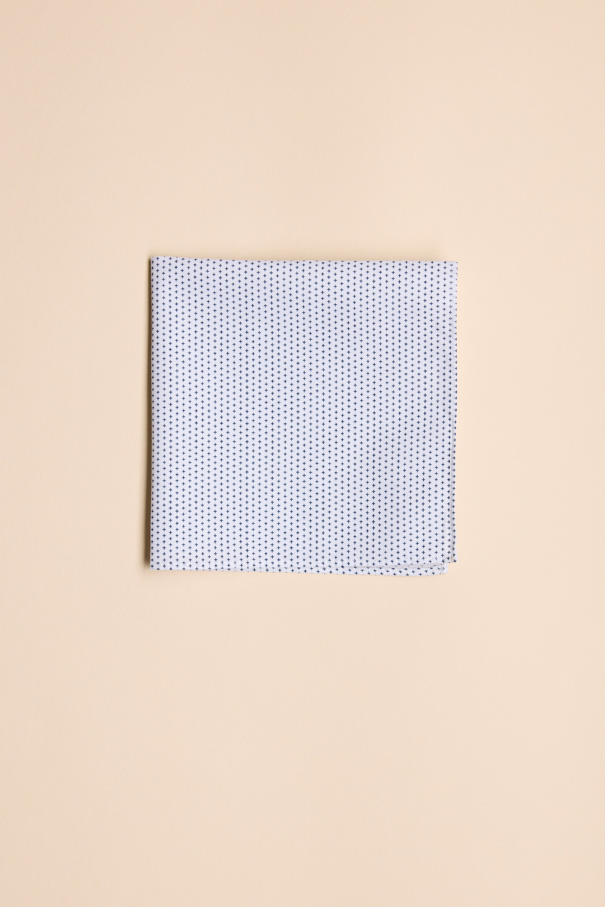 The Barkers Mini Cross Pocket Square, a neatly folded white cotton square with a subtle blue pattern, is displayed on a plain beige background.