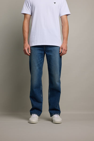 A person stands facing forward in a plain white T-shirt, Barkers Drifter Denim Relax Jean, and white sneakers against a neutral background. The image is cropped at the shoulders.