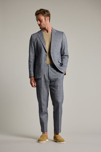 A man stands against a plain background wearing Barkers' Paden Twill Pant, styled with a beige shirt and slip-on shoes. He looks down to his left with one hand in his pocket—an effortless warm-weather look.