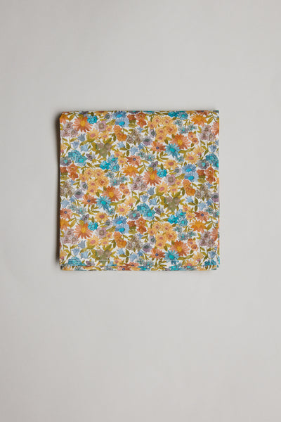 A folded piece of Liberty Sandra Spring PS Tana Lawn cotton fabric by Liberty features a vibrant floral print with orange, blue, yellow, and green flowers, displayed on a plain light background.