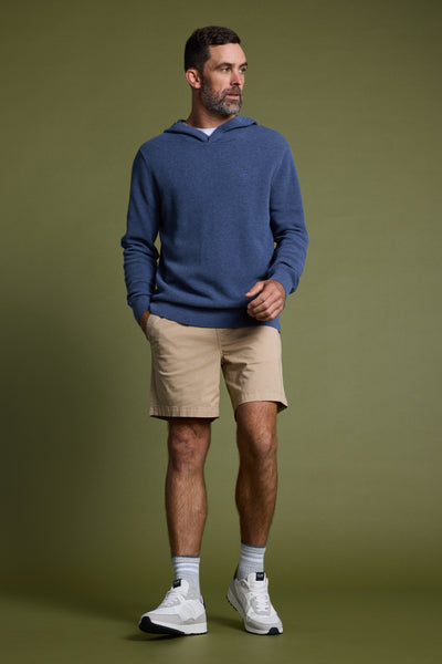 A man with short brown hair and a beard wears the Barkers Lowtide Cotton Hoody, tan shorts, white socks, and white sneakers, standing against an olive green background with one hand in his pocket.