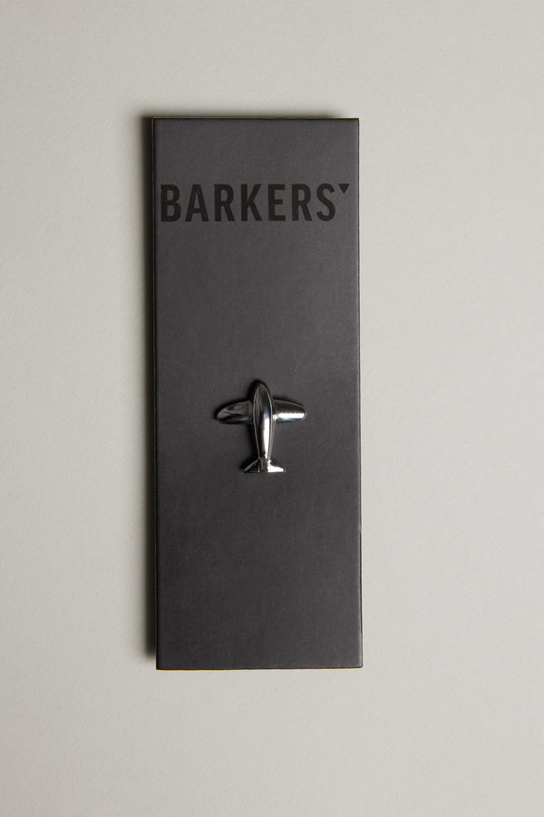 The Jet Plane Lapel Pin by Barkers features a polished silver-tone finish, attached to a black card with the Barkers brand name at the top, all set against a light gray background.