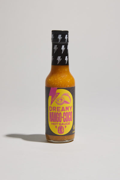 A glass bottle of Culley's Dreamy Mango-Coco Hot Sauce, a tropical blend in yellow and purple packaging with mango and coconut images, finished with a black cap decorated with white lightning bolts.