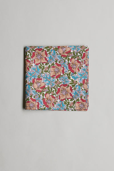 The Liberty Millie Francesca PS by Liberty is a neatly folded floral pocket square, showcasing red, pink, green, and blue patterns on soft Tana Lawn cotton, displayed against a plain light gray background.