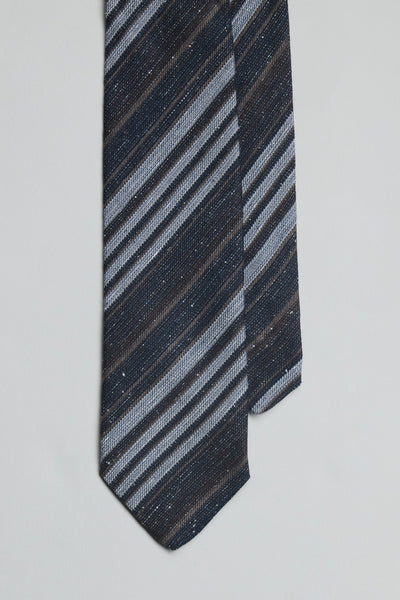 A close-up of the Parisian Scott Stripe Tie by Parisian, featuring handmade diagonal stripes in navy blue, light blue, and gray, displayed on a light background.