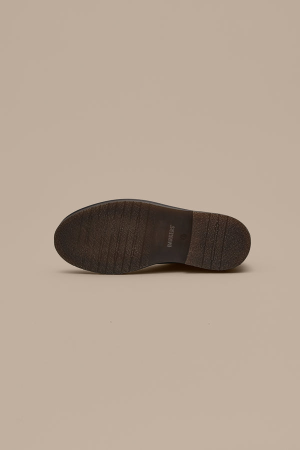 The Barkers Howarth Desert Boot is displayed upside down, highlighting its textured sole against a beige background—a subtle nod to classic Portuguese footwear craftsmanship.