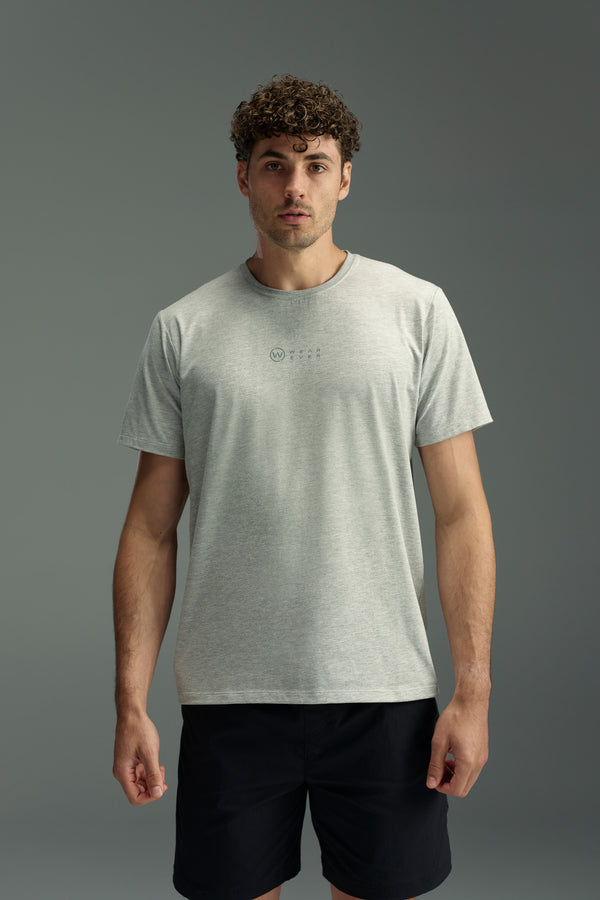 A man with short curly hair wears the WearEver Outbound T-Shirt with moisture wicking, paired with black shorts, standing against a plain grey background and facing forward neutrally.