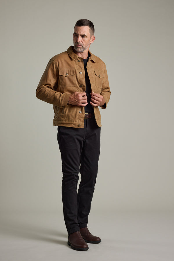 Man wears Barkers Benson Waxed Cotton Sherpa Jacket with black pants and boots.
