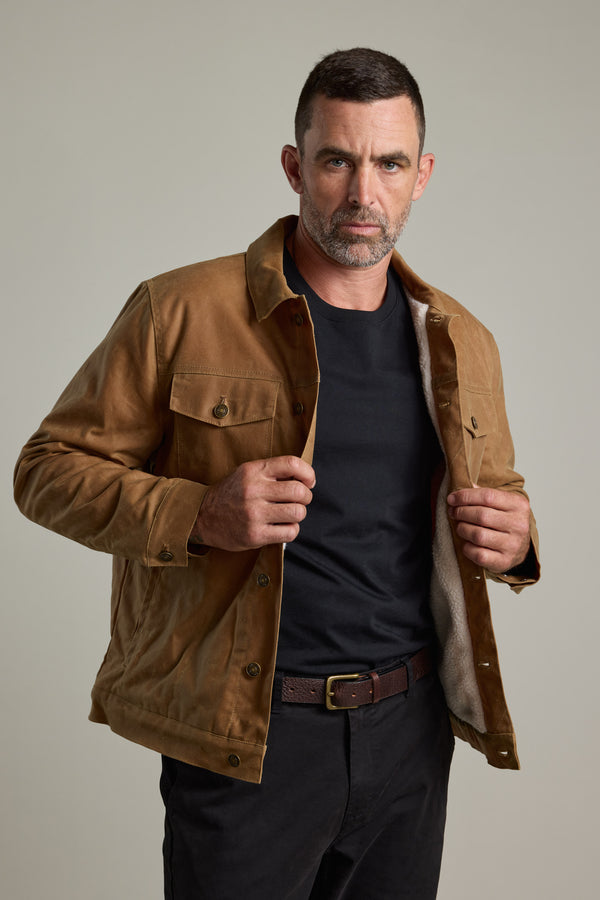 Man in a Barkers Benson Waxed Cotton Sherpa Jacket over a black shirt, looking serious.