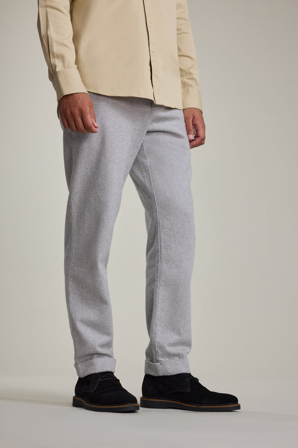 A person is shown from the shoulders down wearing Barkers Dunmore Pant in light gray with a beige long-sleeve shirt and black suede shoes, standing against a plain background.
