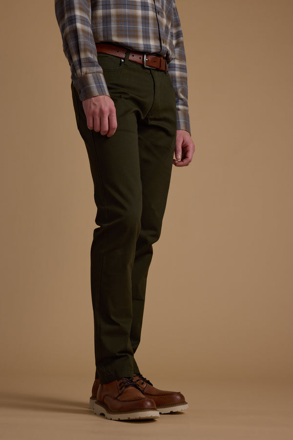 A person wearing a plaid shirt, brown belt, and Barkers Beckett 5-Pocket Pant stands against a plain beige background, with only their lower body visible.