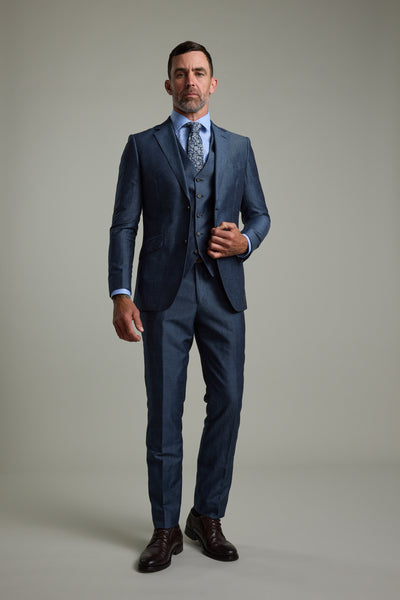 A man models the Barkers Charles Texture Suit Jacket against a plain background, paired with a light blue shirt, patterned tie, and dark brown shoes—showcasing modern summer tailoring for weddings with a direct, neutral gaze.