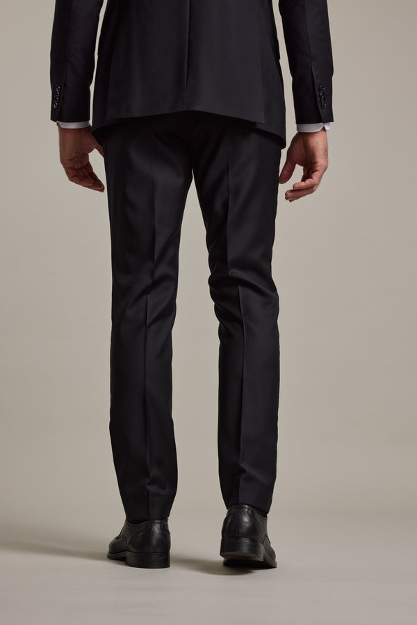 A person stands with their back to the camera, hands relaxed, wearing Barkers' Mayfair ZQrx Suit Trouser—crafted from ethical Merino—against a plain light background.