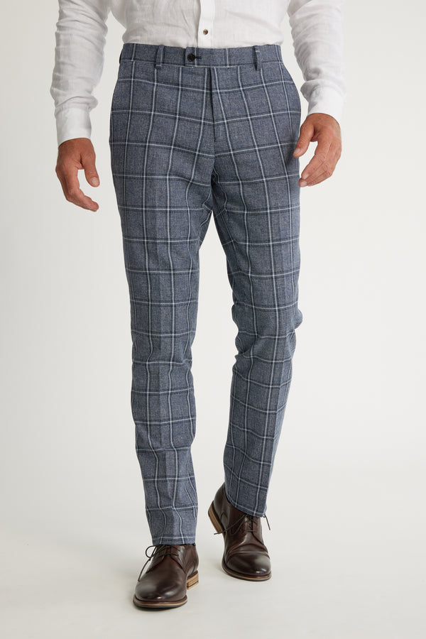 A man models Barkers Highland Check Suit Pant with a white button-up shirt and brown leather dress shoes against a plain white background.