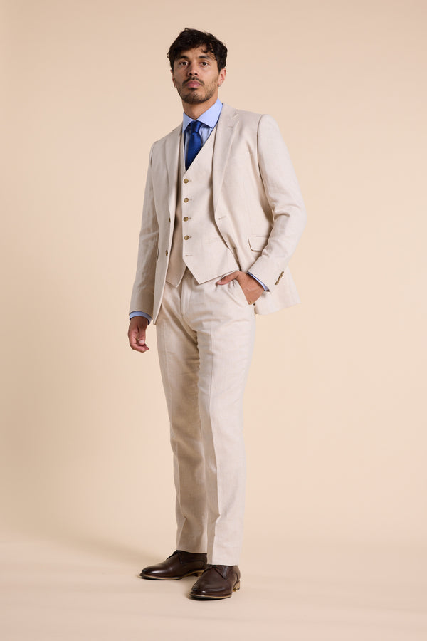 Man in Barkers Thompson Textured Linen Pant with blue shirt, tie, and beige background.