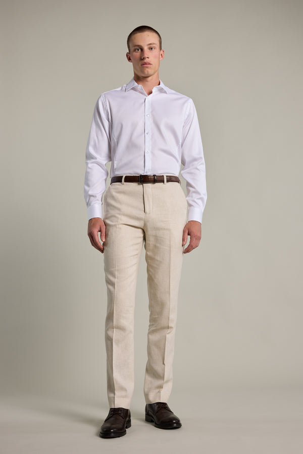 Man in white shirt, Barkers William Texture Linen Pant, and brown shoes stands against background.