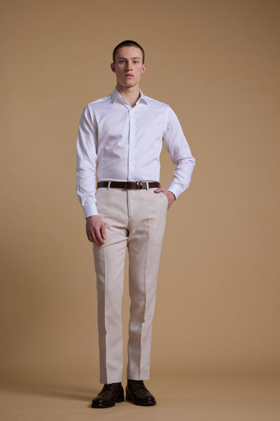 Man in Barkers Aster Texture Business Shirt, tailored beige pants, and dark shoes on tan backdrop.