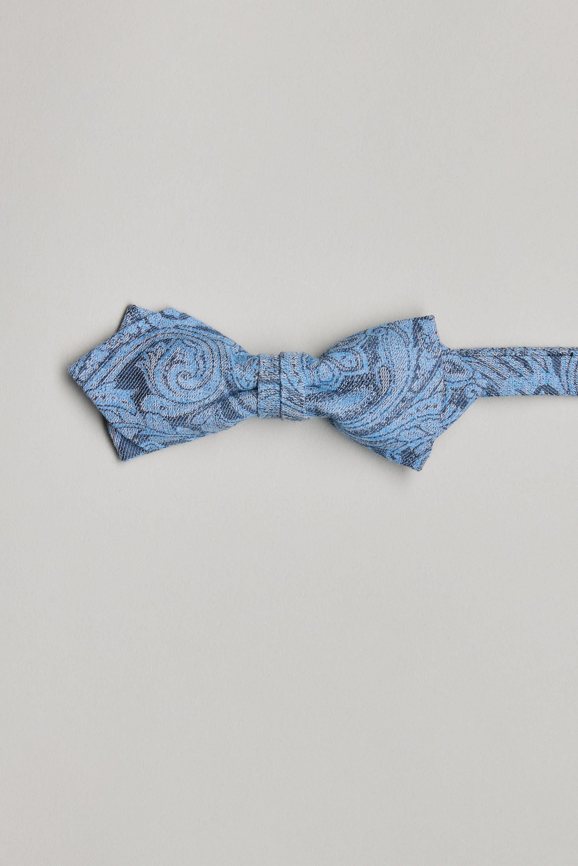 The Barkers Parisian Lincoln Bow Tie, in light blue with swirling paisley and subtle fleur-de-lis patterns, is handmade in New Zealand and shown on a plain white background.