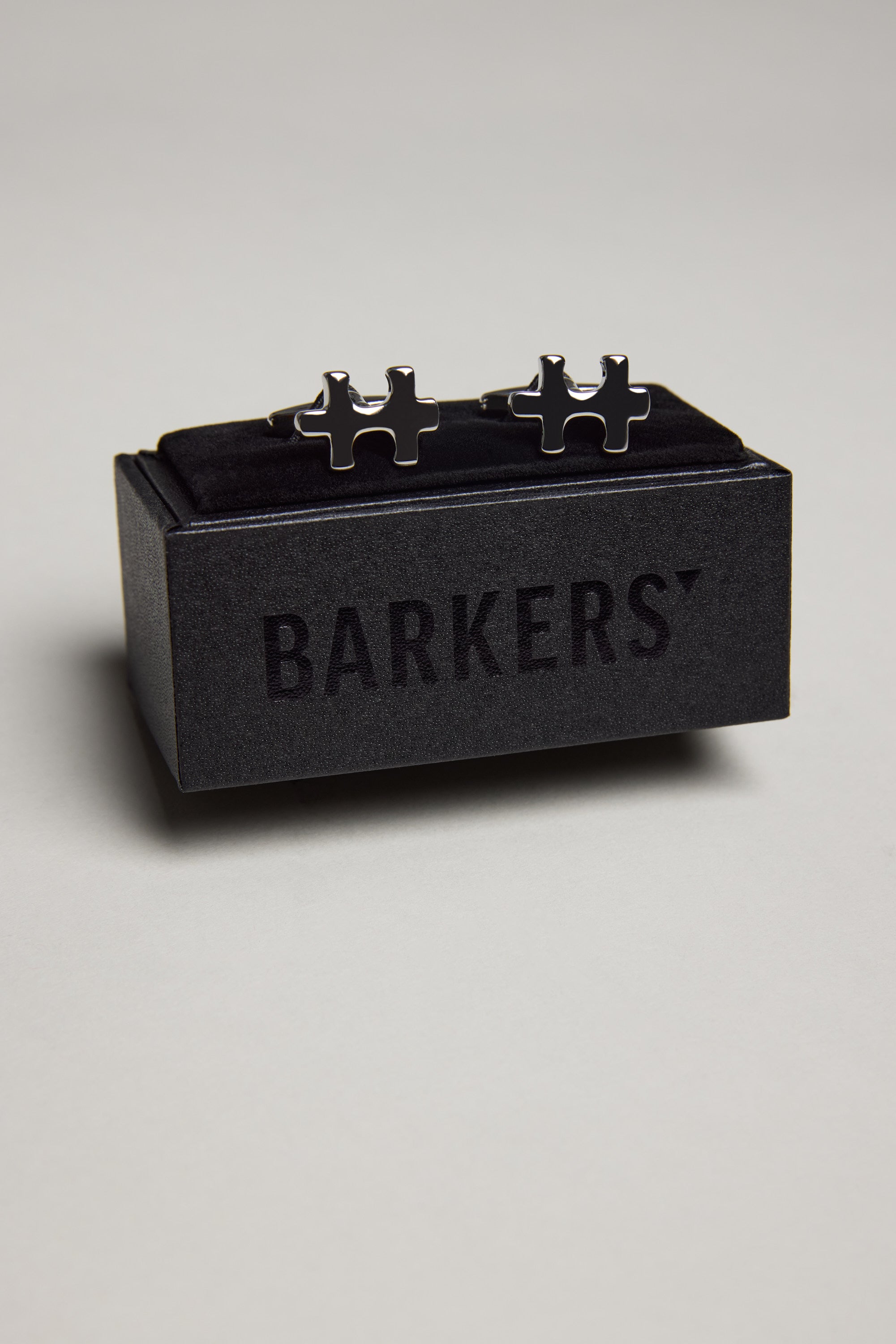 The Barkers Jigsaw Piece Cufflink features a polished silver finish and comes in a black velvet box with the brand name—ideal for French cuff shirts.