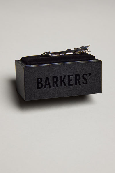 The Barkers Arrow Tie Clip in a polished silver tone sits atop a black box labeled "Barkers," set against a light grey background.