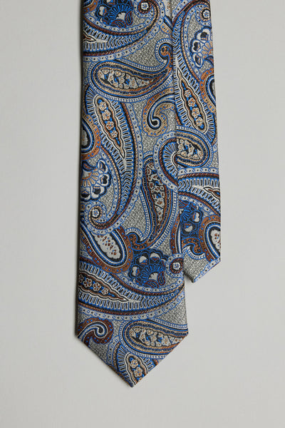The Adrian Paisley Tie by Barkers features an intricate paisley pattern in blue, orange, and beige on a light background, showcased against a plain surface.