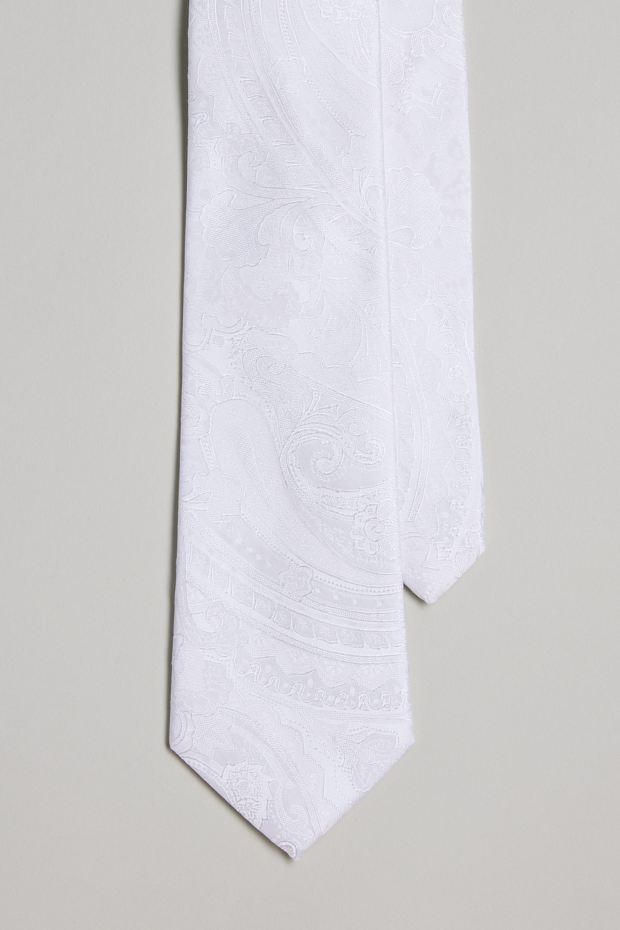 A close-up of the Barkers Kimmel Paisley Tie in white, featuring a subtle paisley pattern against a light gray background—a refined accessory to pair with silk accents or pocket squares.