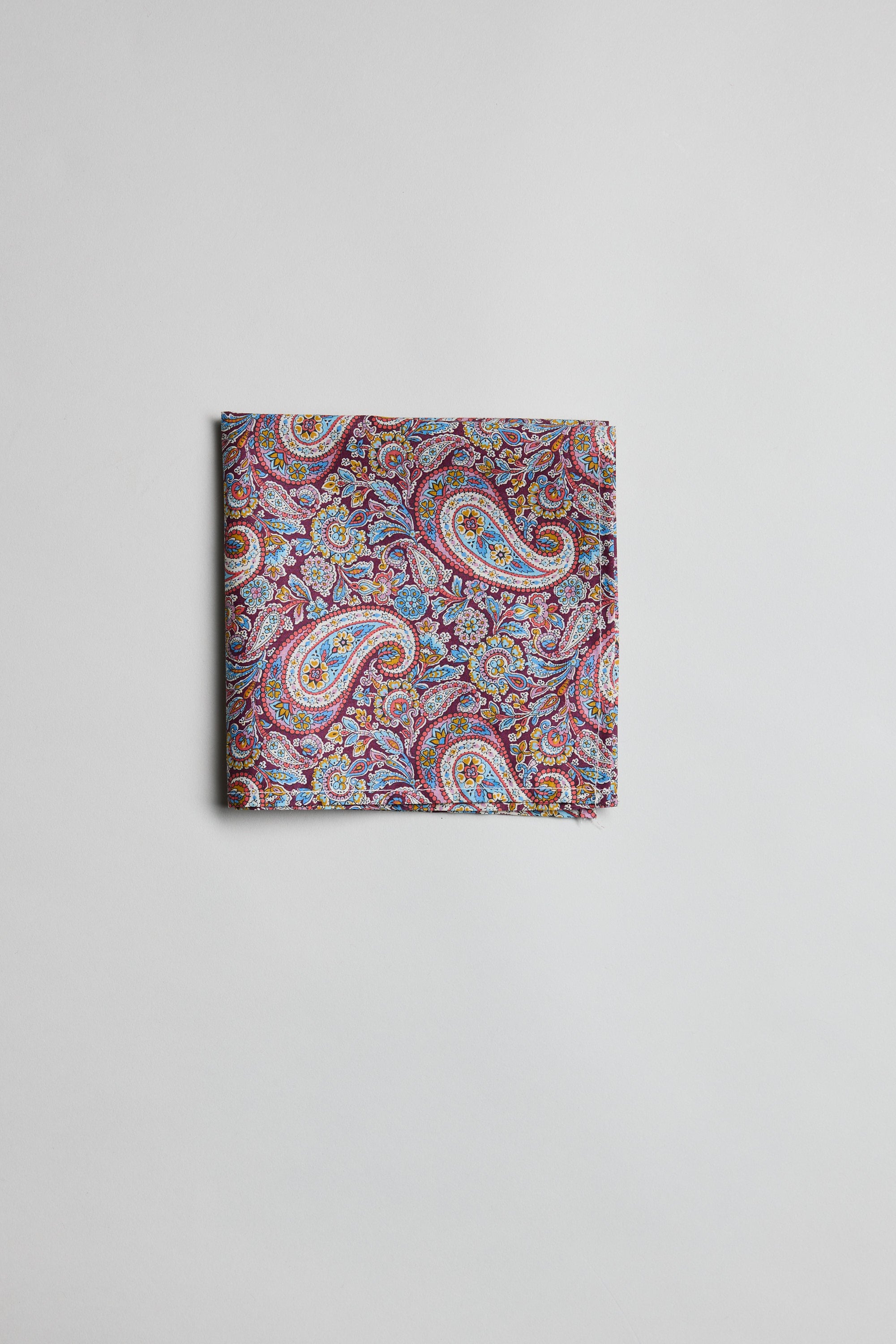 The Liberty Lee Manor PS by Liberty is a folded pocket square with a vibrant paisley design in purple, red, blue, and yellow on soft Tana Lawn cotton, shown against a plain white background.