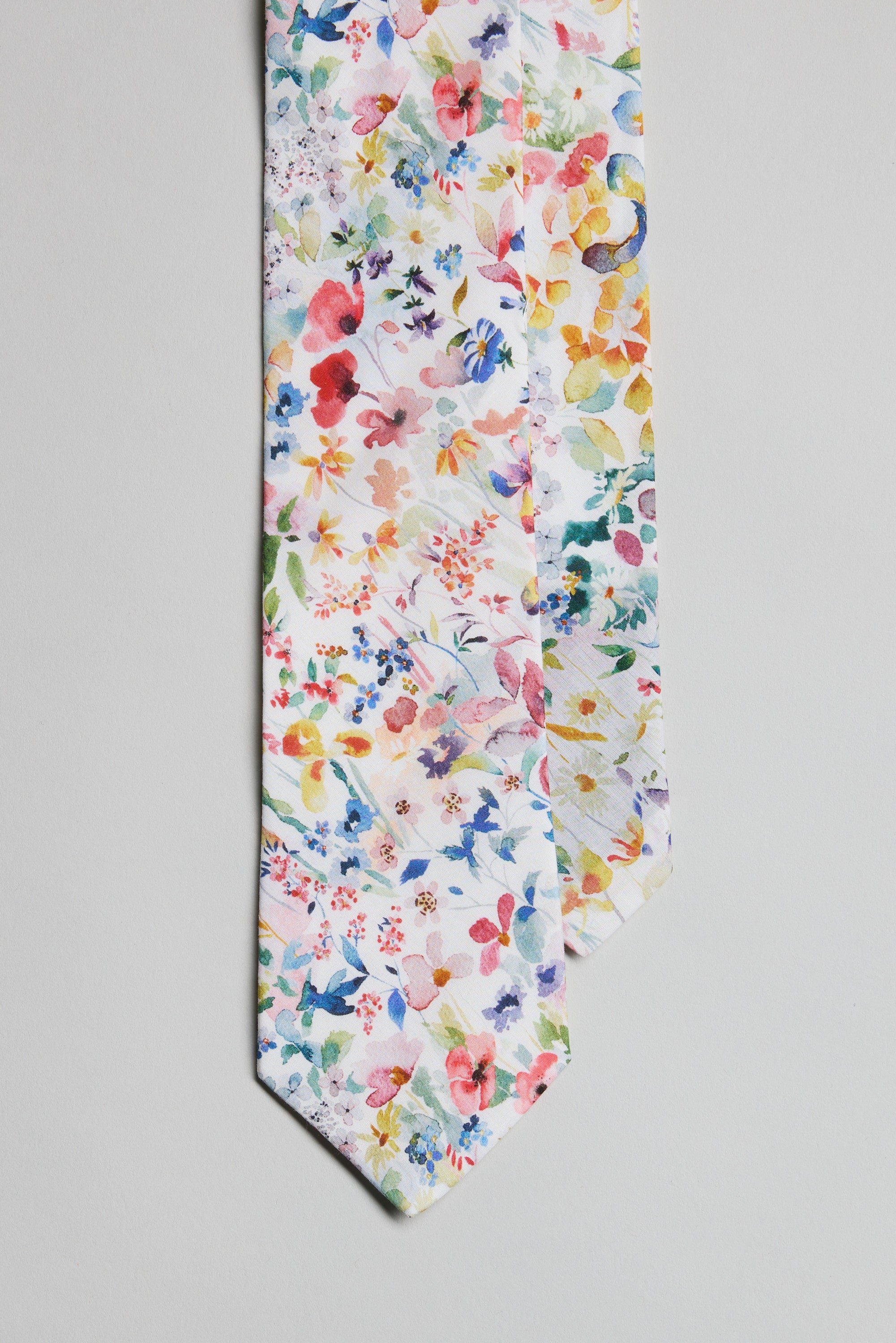 The Liberty Felda Tie by Liberty is made in New Zealand from premium Tana Lawn Cotton, showcasing a vibrant multicolored floral pattern on white with red, yellow, blue, green, and pink flowers.