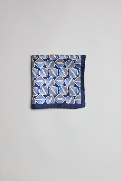 The Parisian Geo Silk PS by Parisian is a silk pocket square with overlapping white and light blue geometric circles and lines, made in New Zealand, shown neatly folded on a plain light gray background.