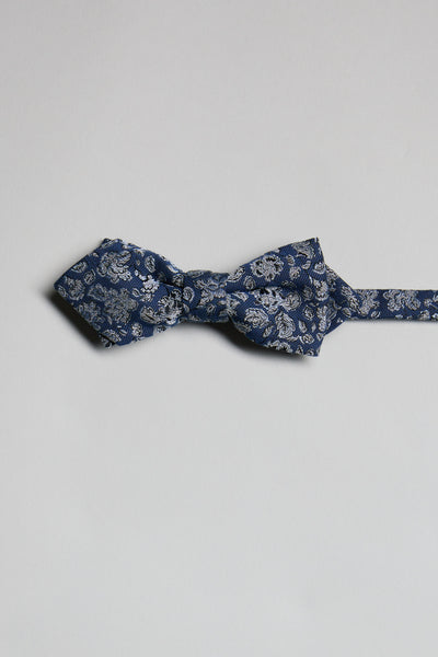 The Parisian Floral Bow Tie by Parisian, featuring a blue paisley pattern, is laid flat on a light gray background with its adjustable neck strap extended to the right.