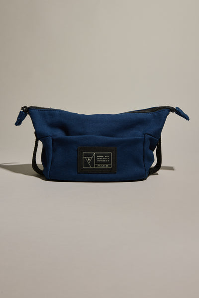 The Barkers Canvas Toiletry Bag is a blue fabric bag with a black zipper and a black rectangular patch featuring white text and graphics on the front, shown against a neutral background.