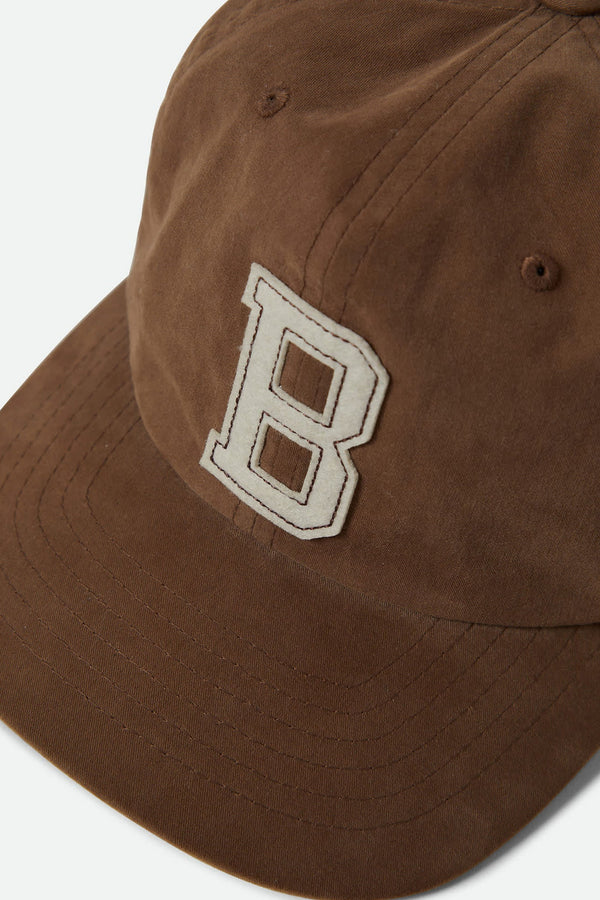 A close-up of the Brixton Big B MP Cap, a brown cotton corduroy 6-panel baseball cap by Brixton, featuring a large white embroidered "B" on the front with visible stitching and seams.