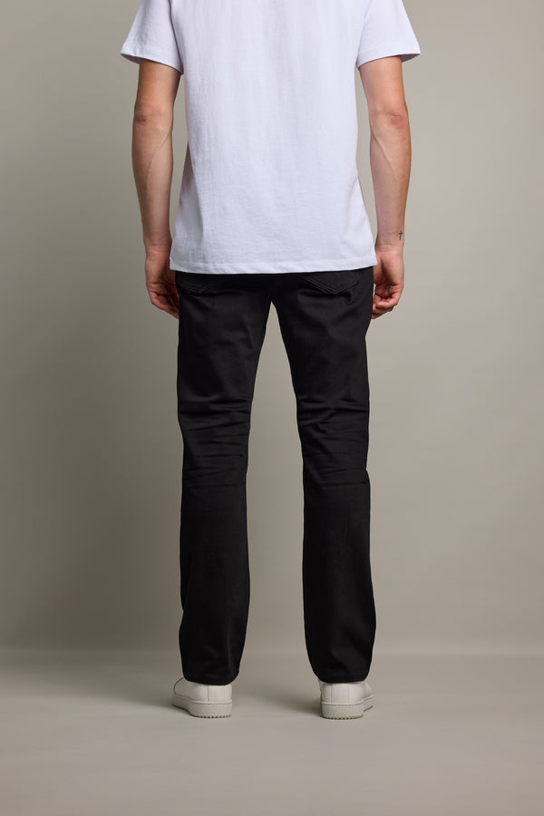 Person stands facing away in a white tee and Barkers Wanderer Denim Straight Jean.