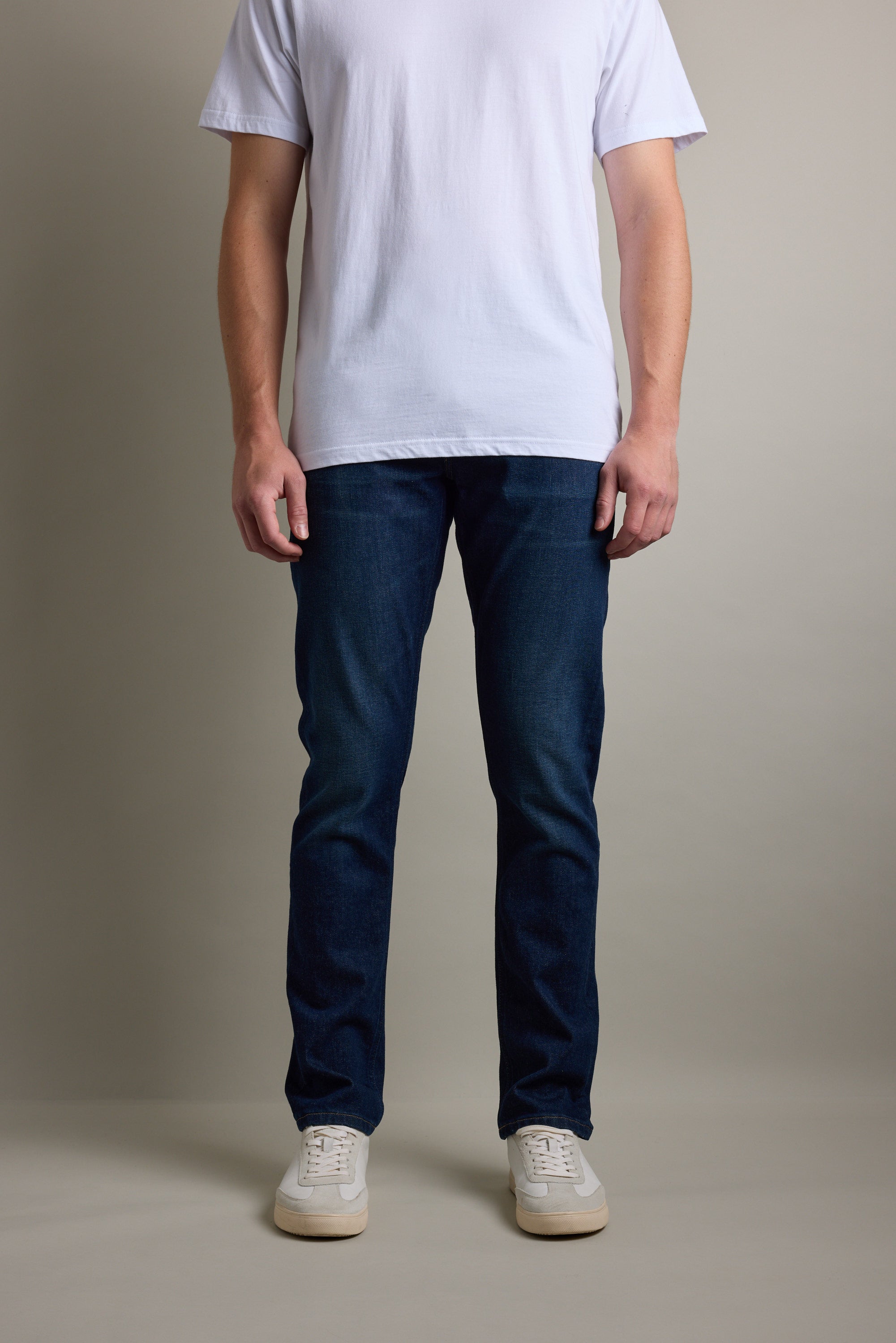 Person wearing a white t-shirt, Barkers Nomad Denim Taper Jean, and white sneakers, facing forward.