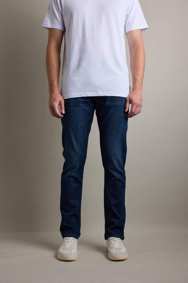 Person wearing a white t-shirt, Barkers Nomad Denim Taper Jean, and white sneakers, facing forward.