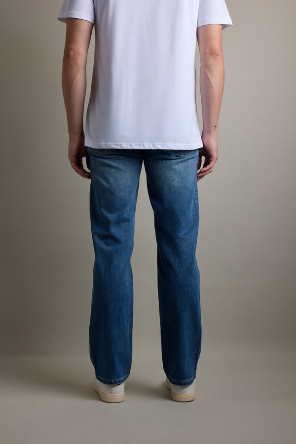 Person facing away, wearing Barkers Drifter Denim Relax Jean, white tee, and white shoes.