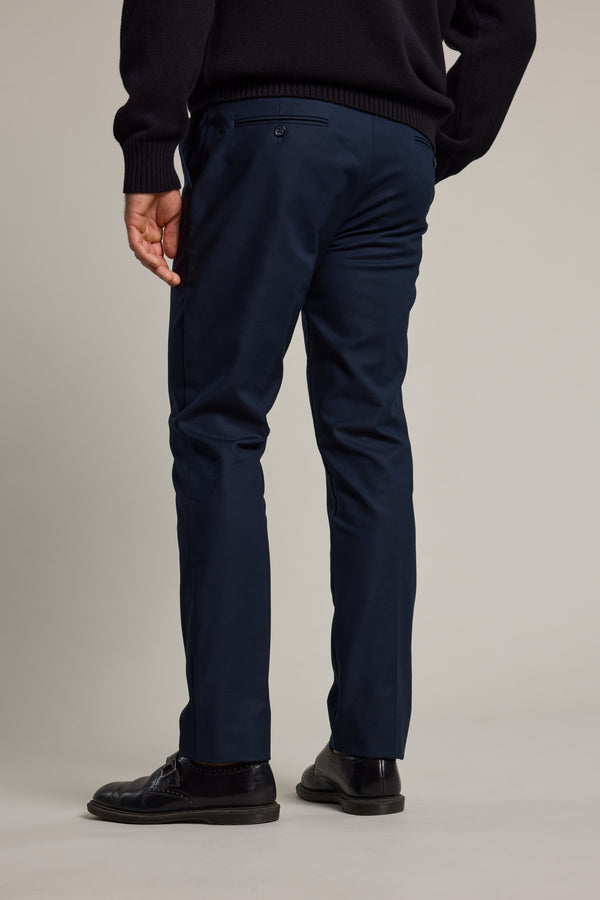 A person stands facing away, wearing a black sweater, black dress shoes, and Barkers' Lyndon Cotton Pants against a plain, light background.