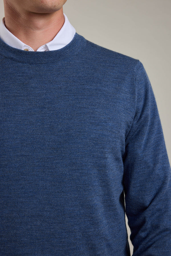 A person wears a Barkers Skyland ZQrx Merino Crew sweater, made from sustainable New Zealand merino wool, layered over a white collared shirt. The photo shows their shoulders and upper chest against a plain background, face partly out of frame.