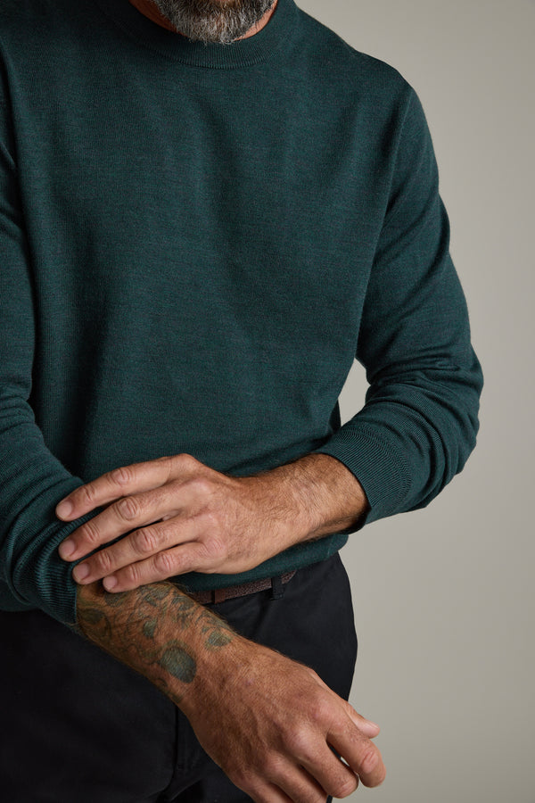 Man in a Barkers Skyland ZQrx Merino Crew rolling up his sleeve, showing a tattoo.