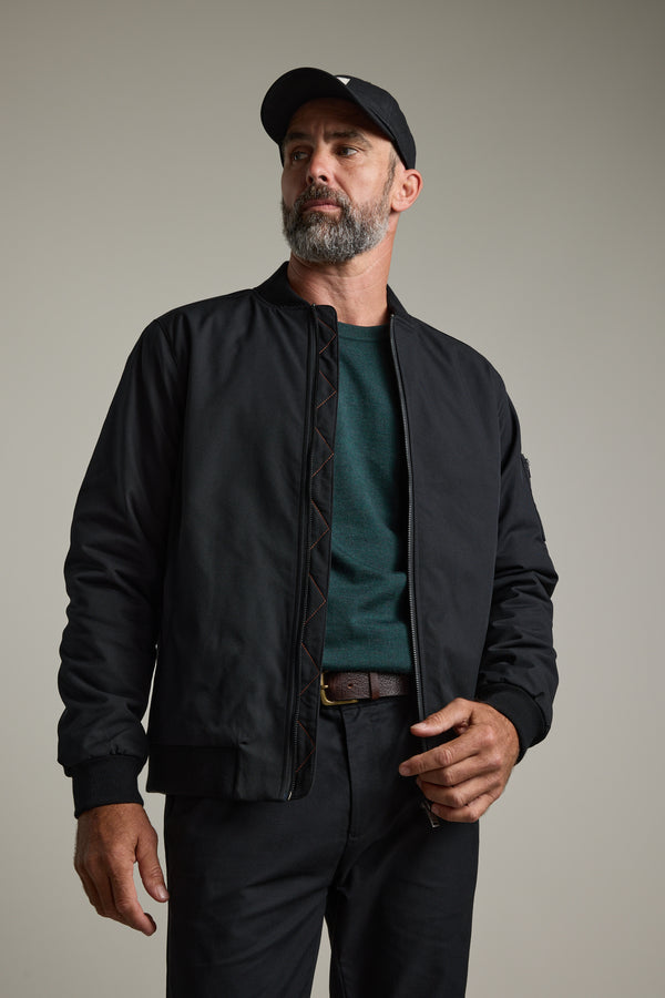 Bearded man in black jacket and Barkers Skyland ZQrx Merino Crew, standing indoors.