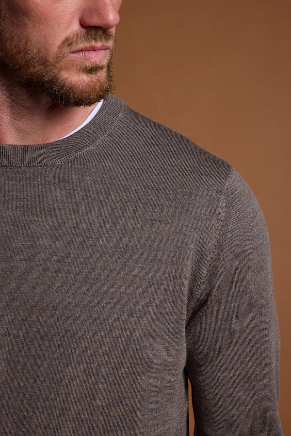 A close-up of a bearded man wearing the Barkers Skyland ZQrx Merino Crew over a white shirt, set against a plain brown background. Only the lower part of his face and neck are visible.