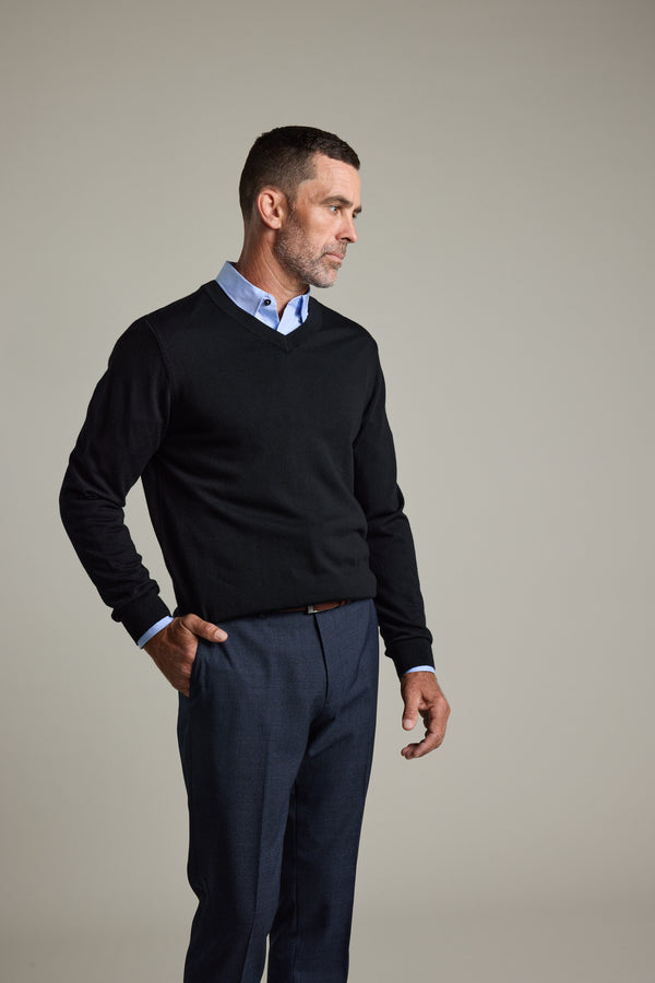Man in a Barkers Skyland ZQrx Merino Vee sweater over a blue shirt stands by a plain background.
