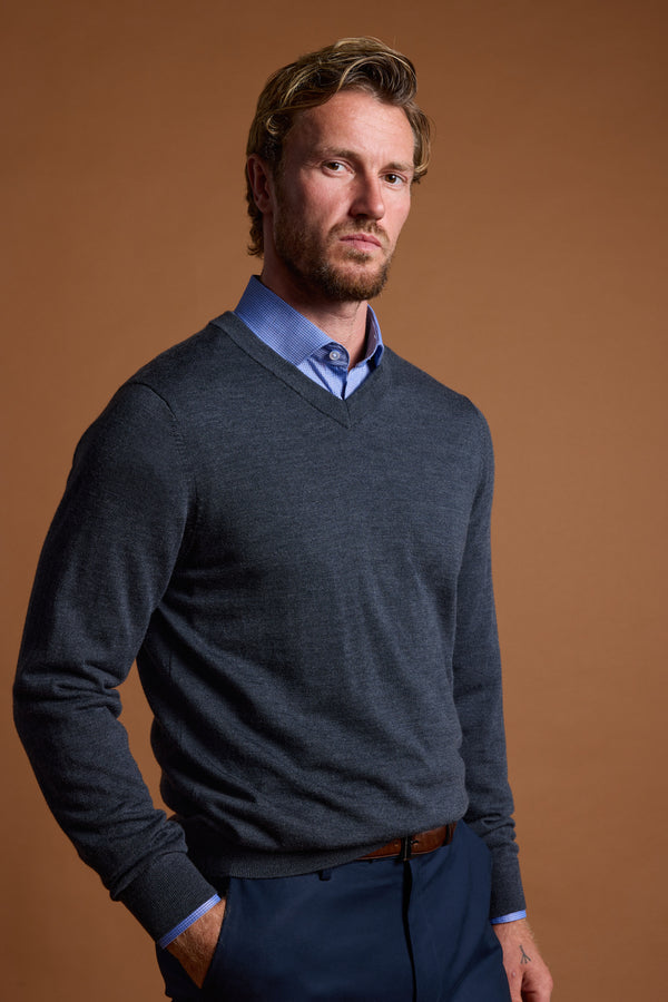 Man in Barkers Skyland ZQrx Merino Vee poses with hands in pockets against a brown background.