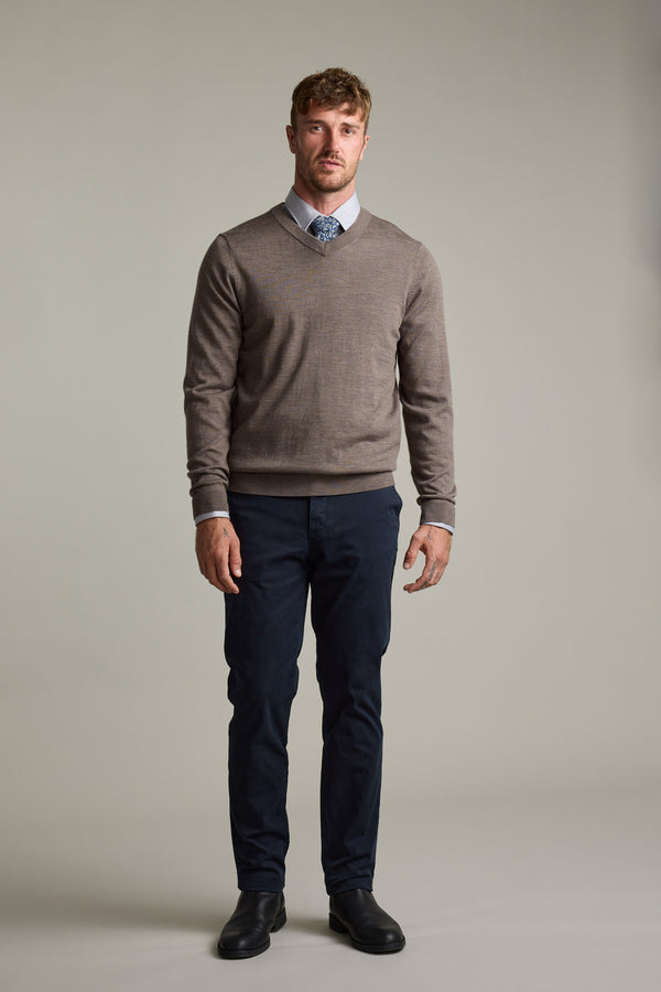 Man wearing Barkers Skyland ZQrx Merino Vee sweater, blue shirt, tie, dark pants, black shoes indoors.