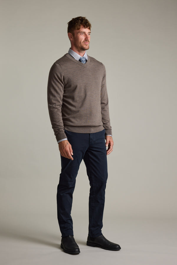 Man wears Barkers Skyland ZQrx Merino Vee sweater with blue shirt, tie, pants, and black shoes.