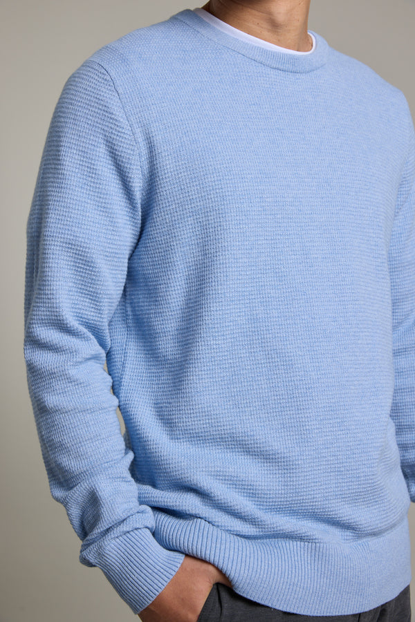 A person wearing the Barkers Dunes Texture Crew sweater in light blue over a white shirt stands with one hand in their pocket against a neutral background, their face partially out of frame.