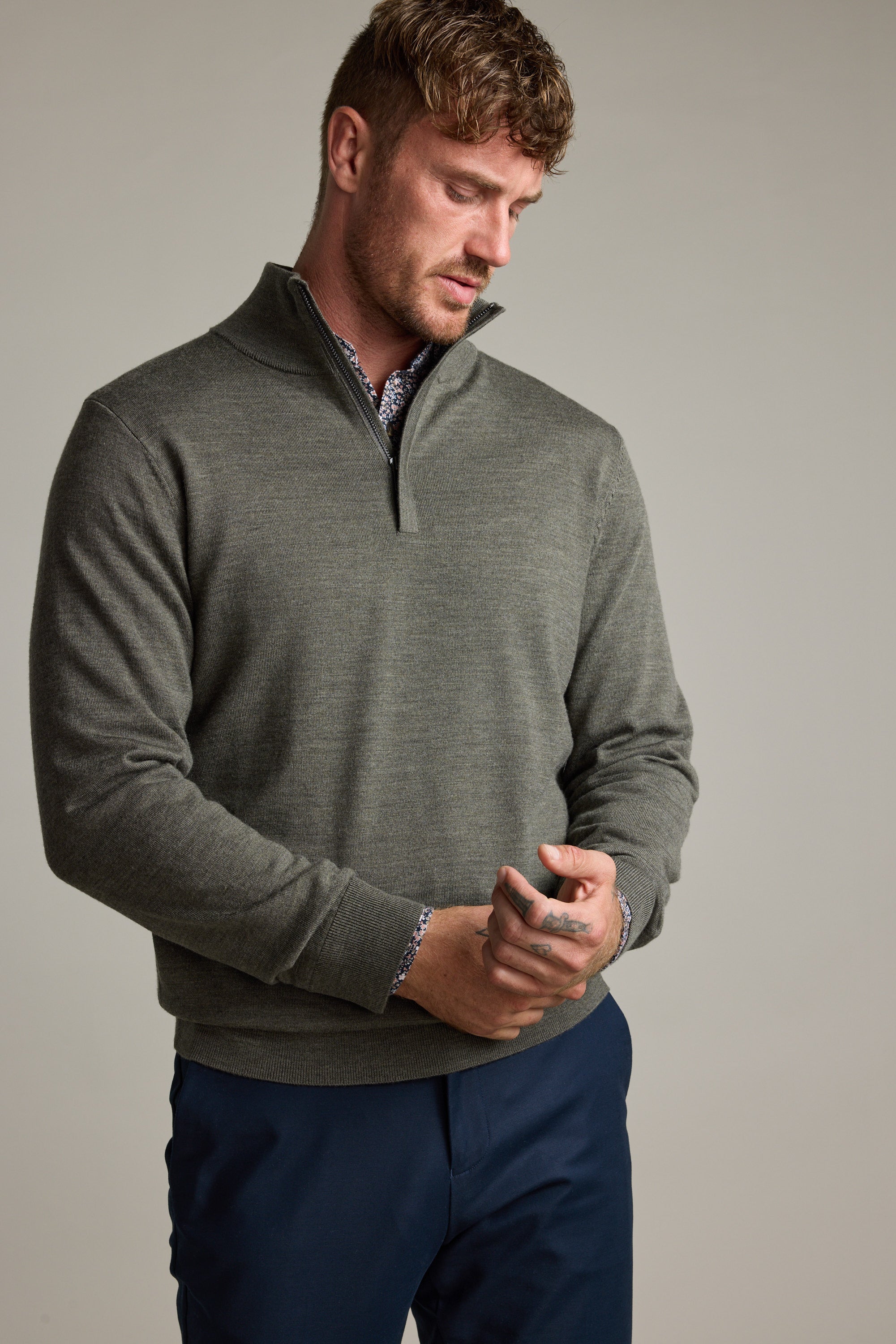 Man adjusts cuff in Barkers Skyland ZQRX Merino 1/4 Zip and navy pants, looking down.