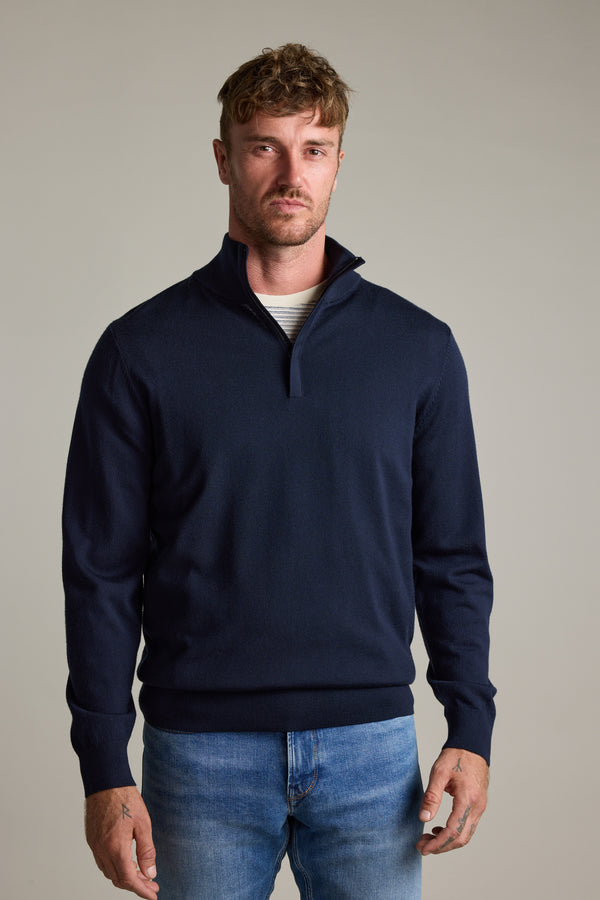 Man in a Barkers Skyland ZQRX Merino 1/4 Zip and jeans stands against a light gray background.